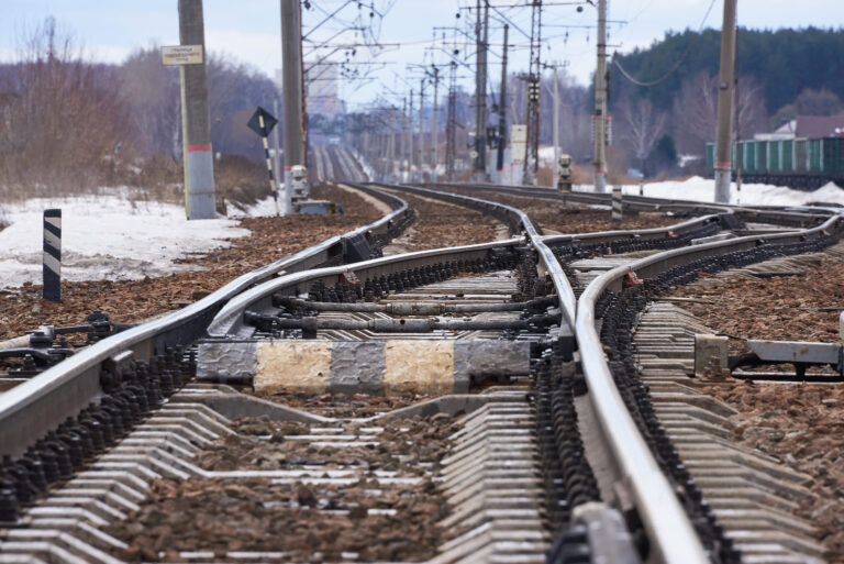 Railway points on an electrified line with snow alongside the tracks in winter.